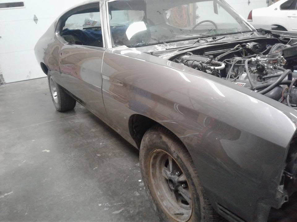Gray classic car project with its hood removed inside the shop